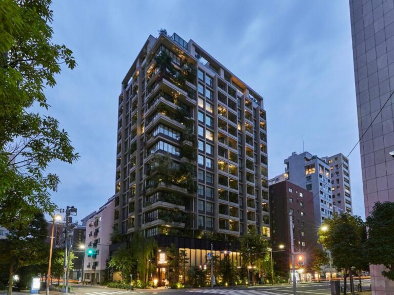 位於東京市區的 HAMACHO HOTEL TOKYO 飯店外觀，建築立面的陽台巧妙結合了豐富的綠意植栽與洗鍊的幾何線條，在都會街景中打造出獨樹一格的自然美學。